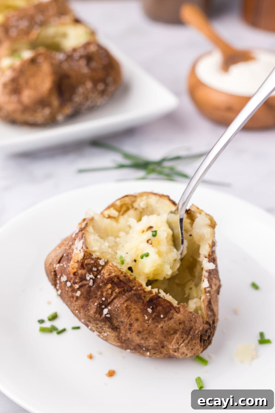 Baked Potato Perfection 9 Baked Potato split open on a plate with a fork in it