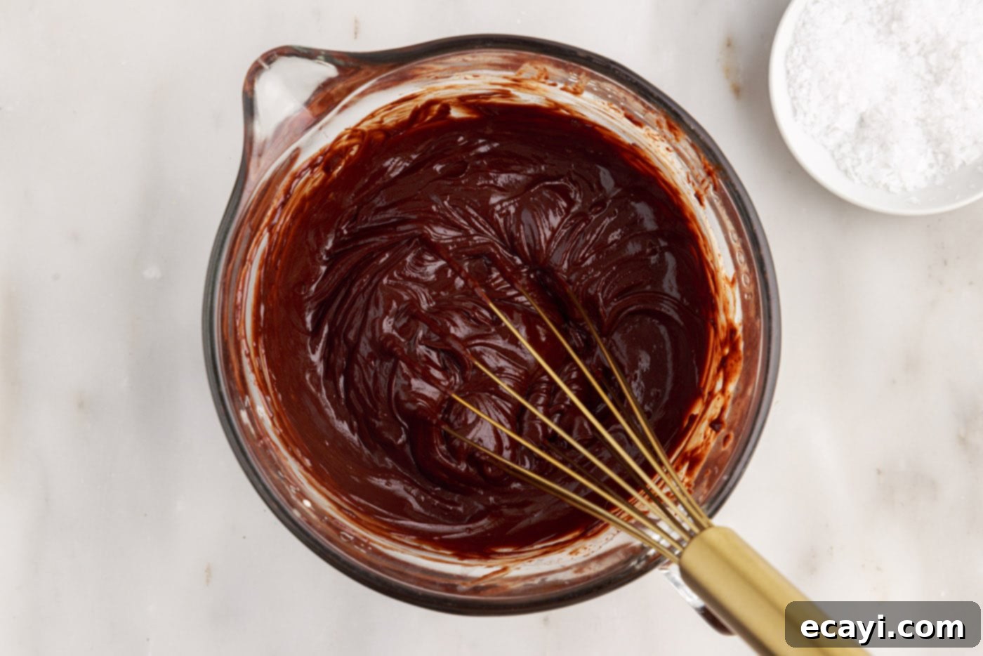 Golden Caramel Indulgence 15 Whisking chocolate ganache in a bowl until it is smooth and rich.