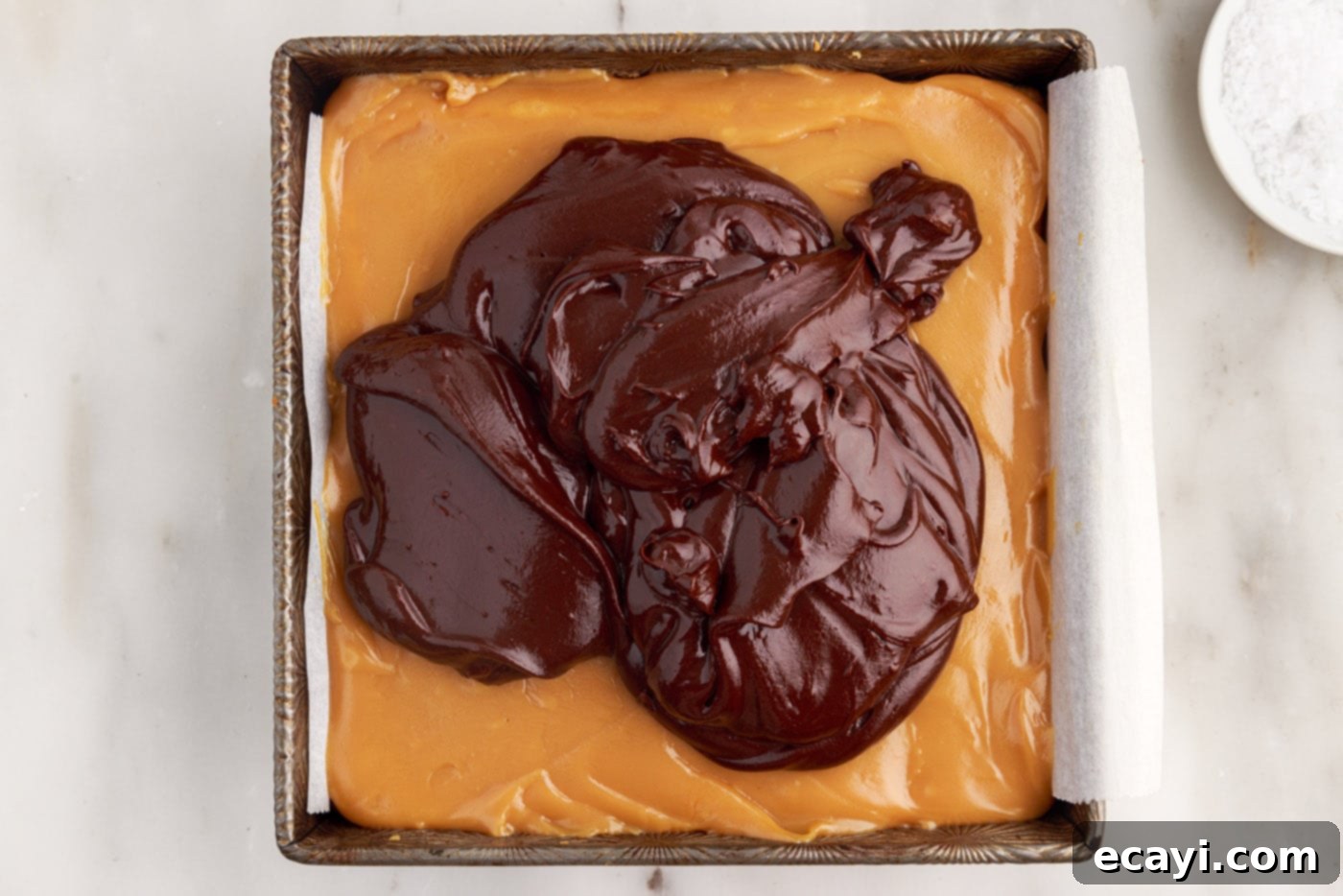 Golden Caramel Indulgence 16 Smooth chocolate ganache being poured over the set caramel layer in the baking dish.