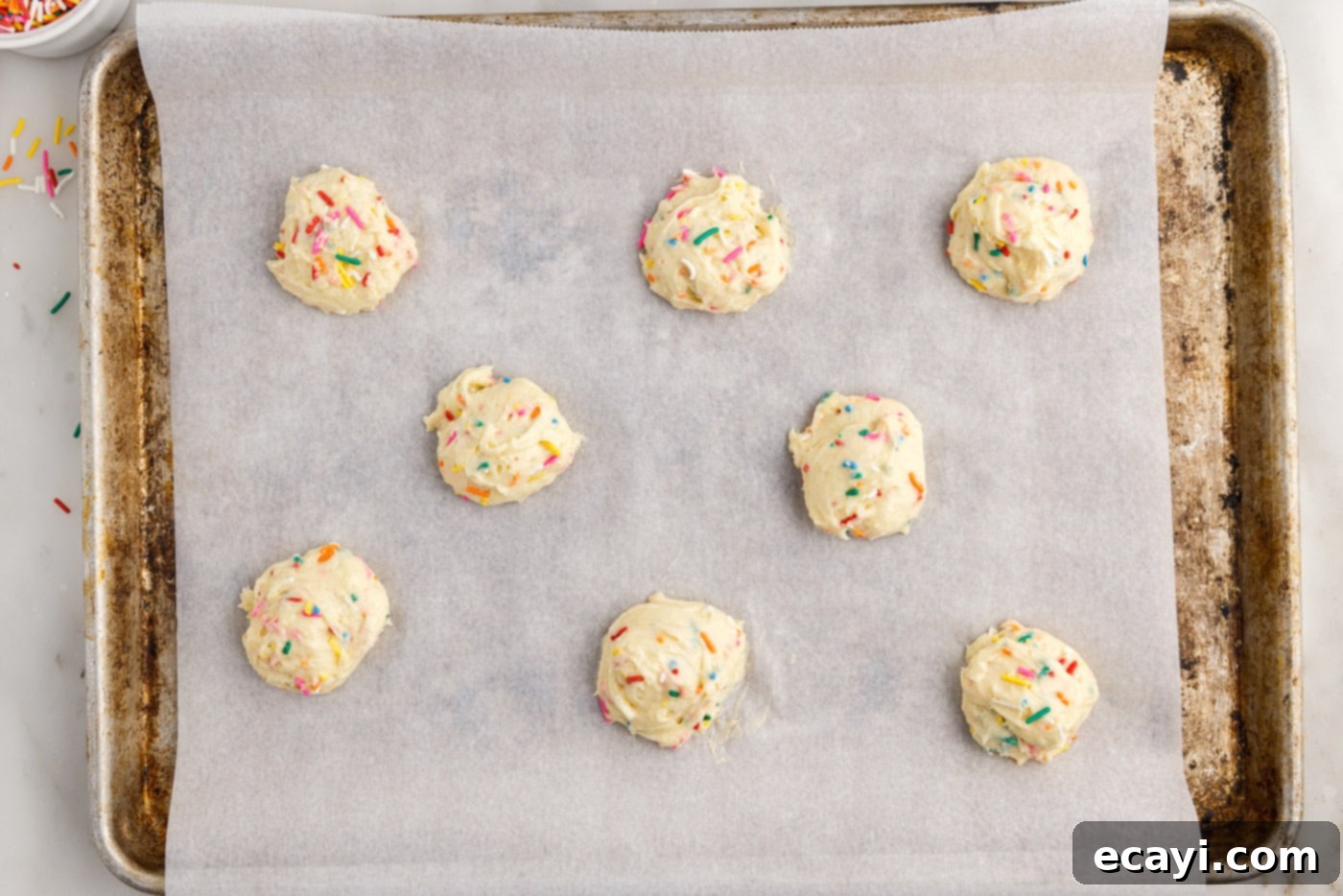 Easy Funfetti Cake Mix Cookies 7 Funfetti cookie dough balls, perfectly scooped and arranged on a parchment-lined baking sheet, ready for the oven.