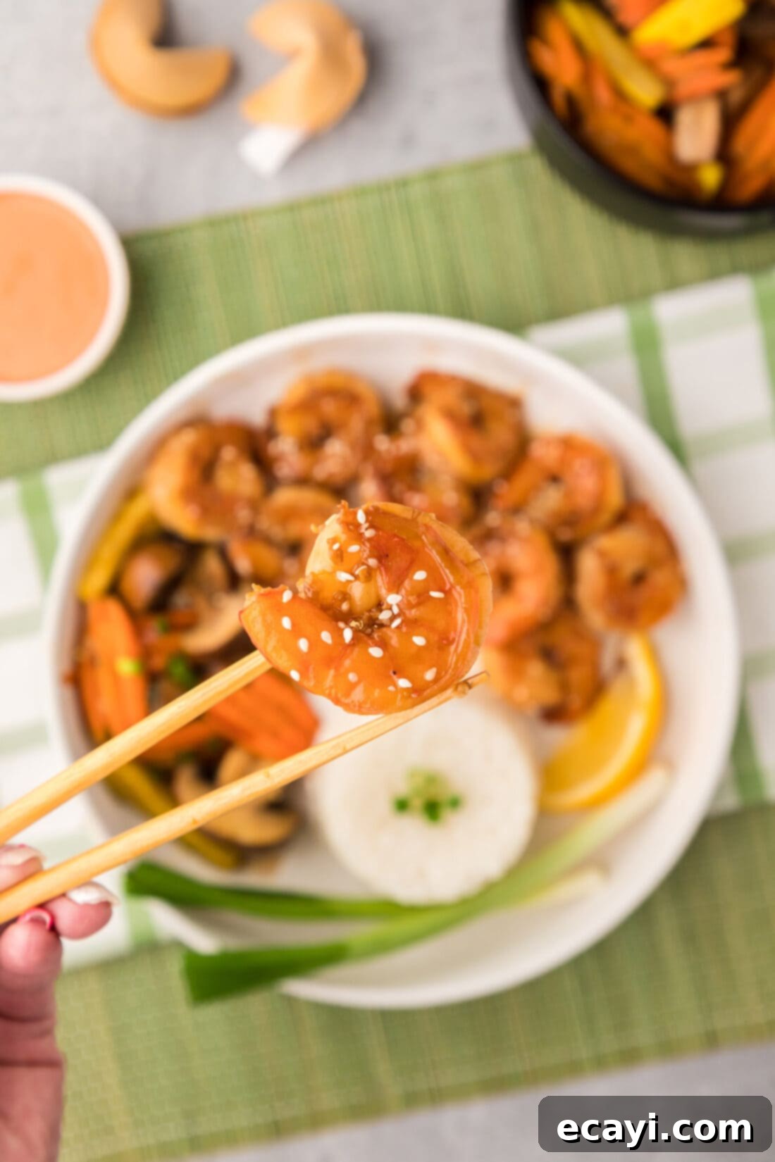 Sizzling Hibachi Shrimp 2 Chopsticks holding up a piece of perfectly cooked Hibachi Shrimp, showcasing its beautiful color and juicy texture.