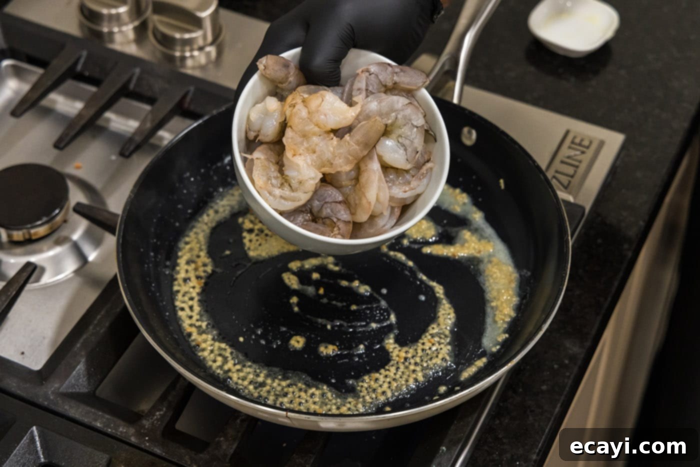 Sizzling Hibachi Shrimp 6 Raw shrimp being added to a hot skillet with melted butter and fragrant garlic, ready for searing.