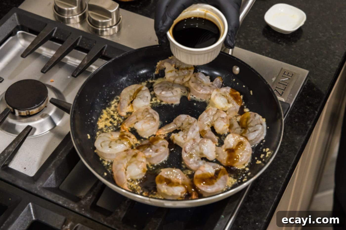 Sizzling Hibachi Shrimp 8 Soy sauce being carefully added to the pan, joining the sesame oil, oyster sauce, and shrimp, completing the sauce blend.