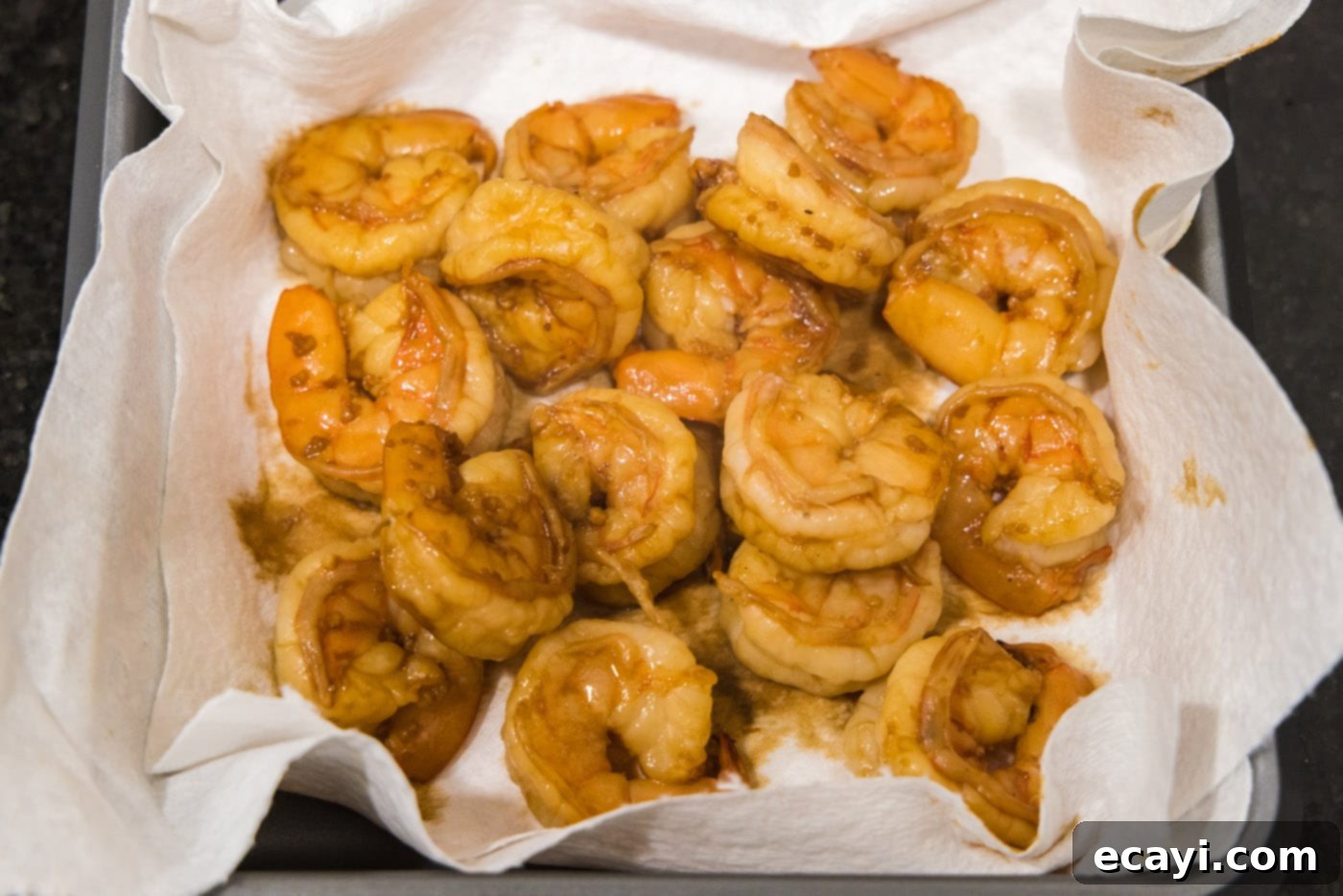 Sizzling Hibachi Shrimp 10 Cooked hibachi shrimp carefully placed on a paper towel-lined plate to drain, ensuring optimal texture before serving.