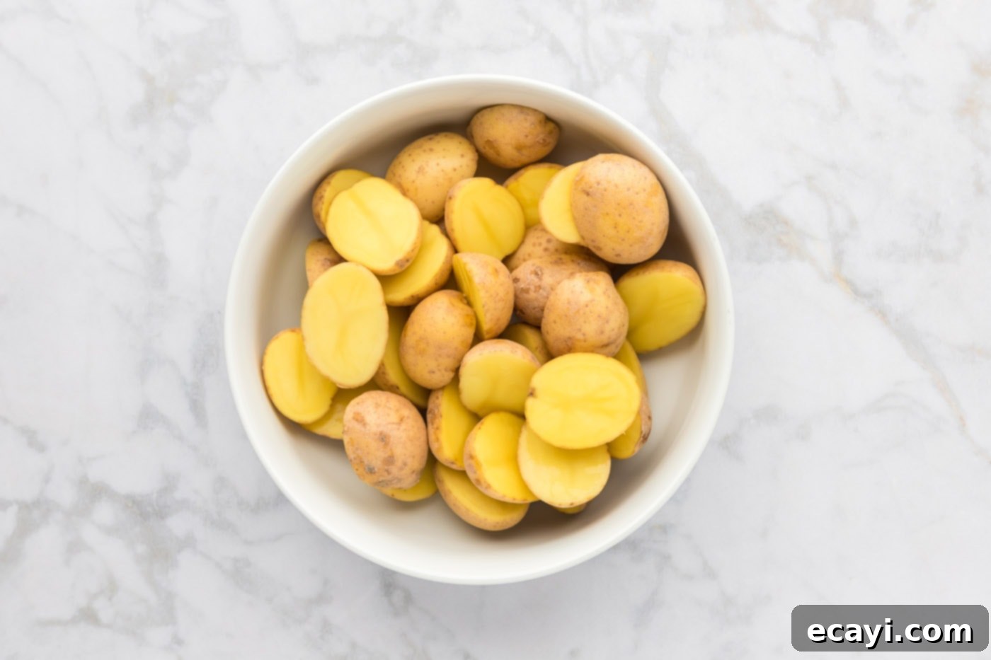 Crispy Parmesan Potatoes 6 Sliced Yukon Gold potatoes resting in a large mixing bowl, ready for seasoning