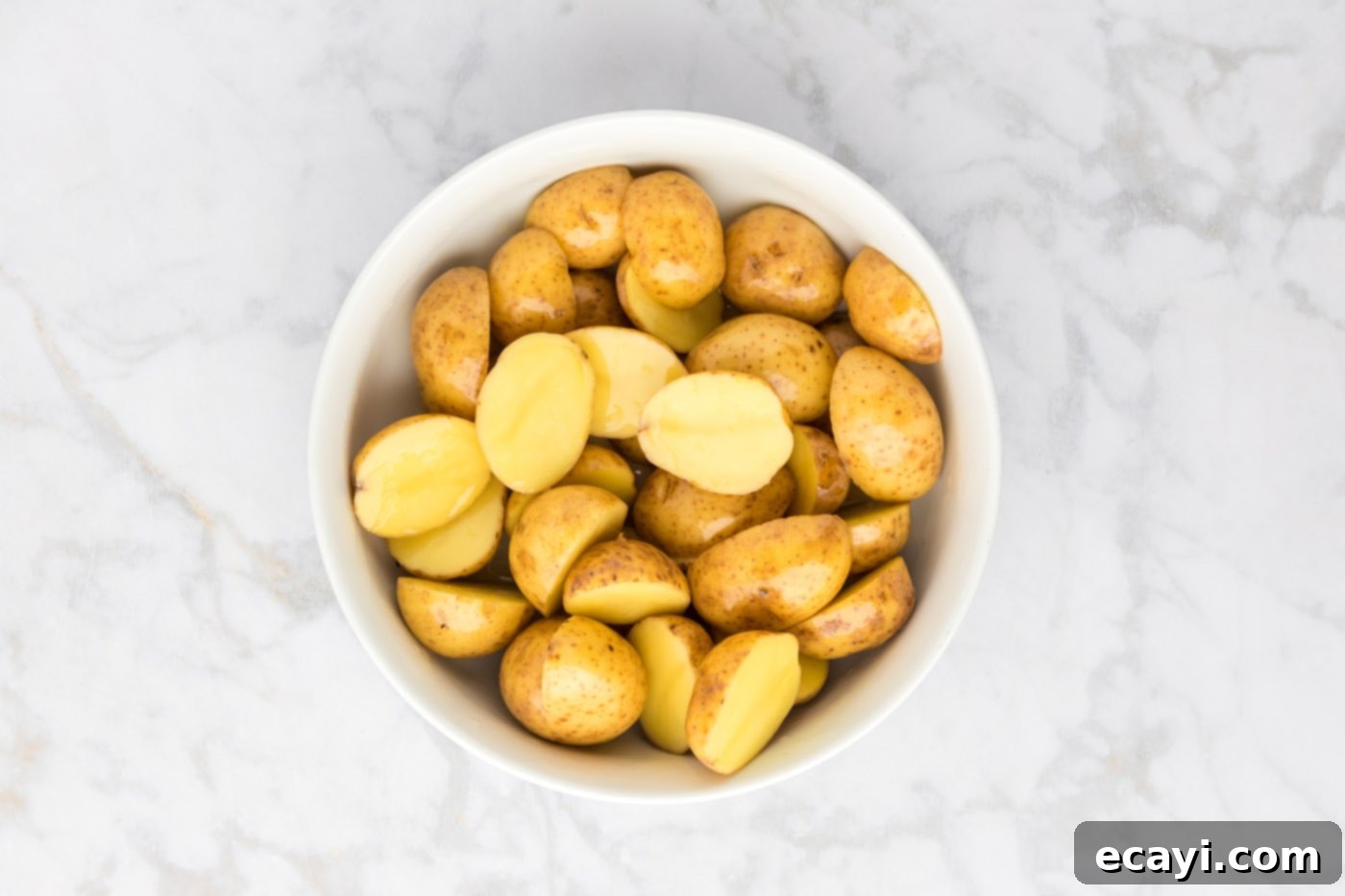 Crispy Parmesan Potatoes 9 Sliced potatoes after being thoroughly tossed with olive oil, glistening and ready for seasoning