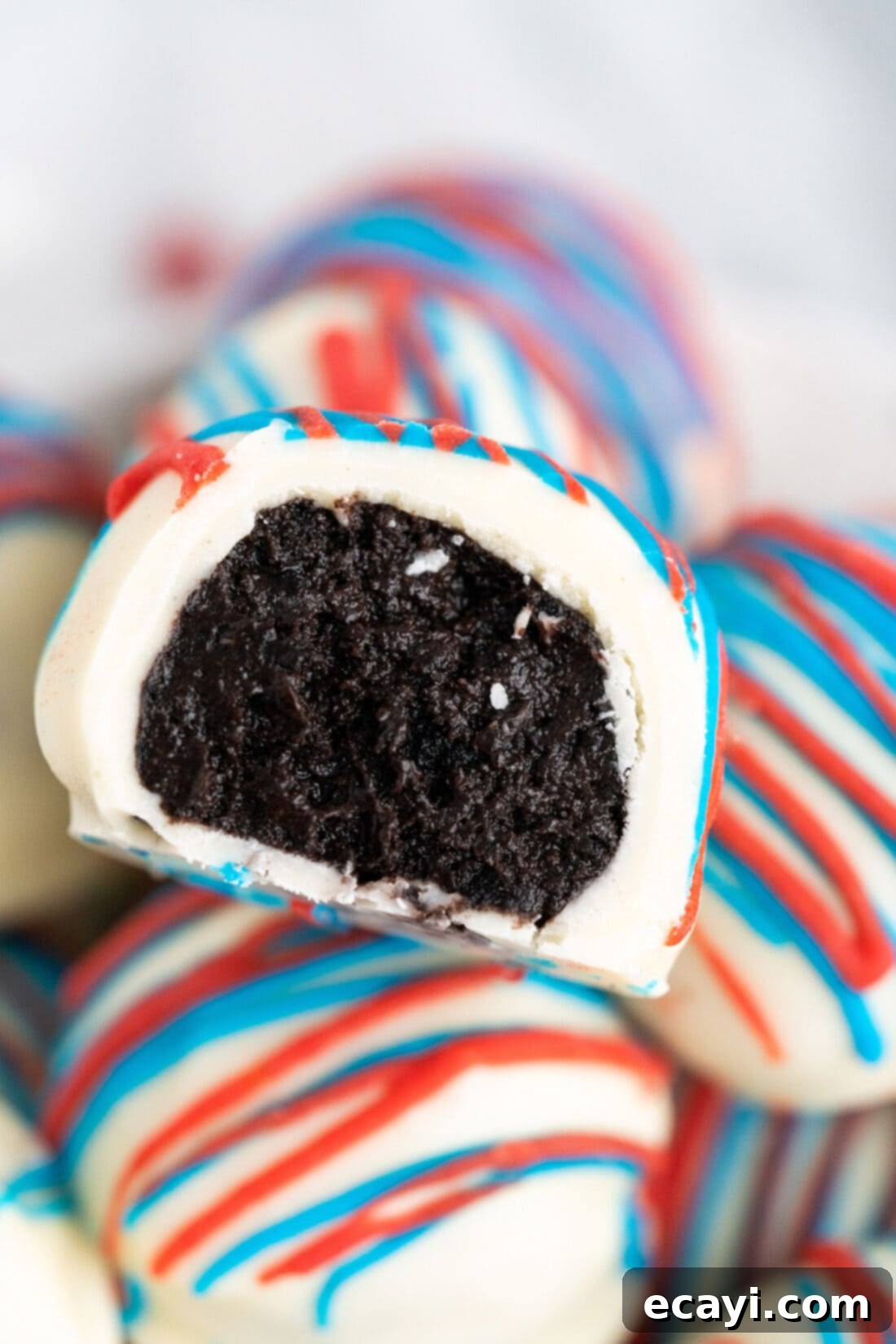 Stars and Stripes Oreo Truffles 2 Close up photo of a Red White and Blue Oreo Truffle with a bite taken out, showing the cookie and cream cheese filling