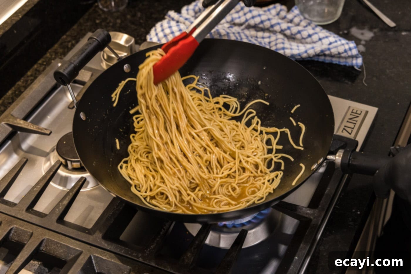 Sweet Sticky Teriyaki Noodles 9 tongs picking up teriyaki noodles in a wok