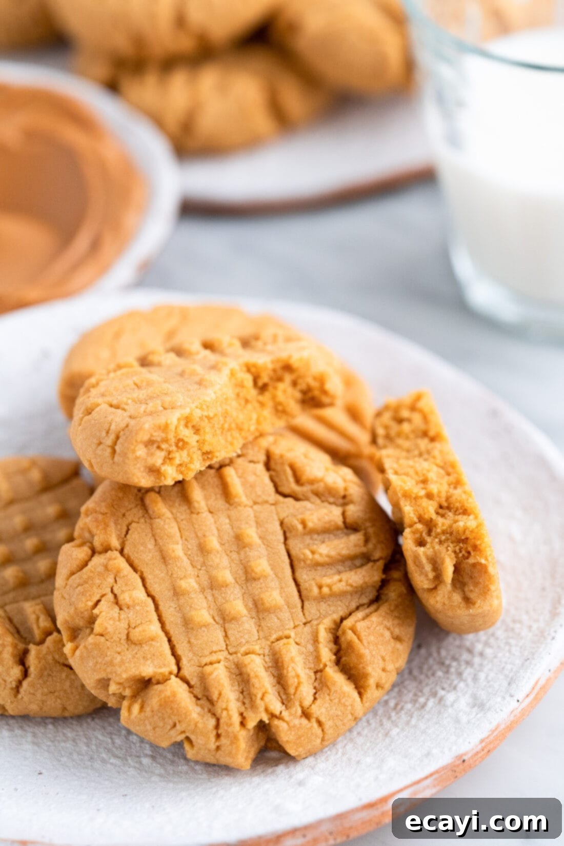 Peanut Butter Cake Mix Delights 2 Peanut Butter Cake Mix Cookies on a plate with the top one broken in half, showing their soft texture.