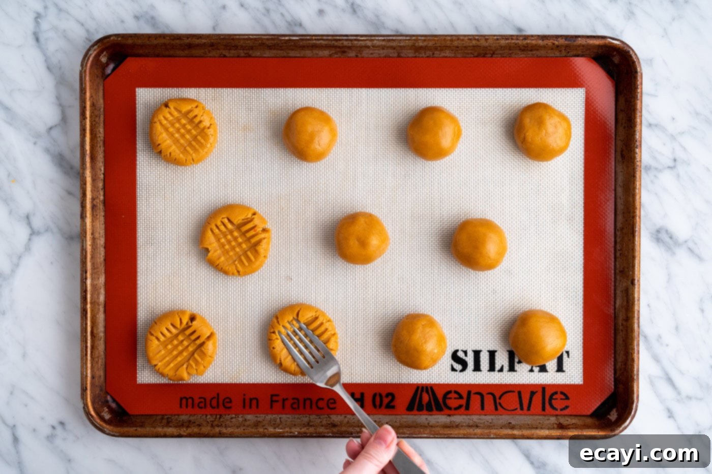 Peanut Butter Cake Mix Delights 13 Two rows of cookie dough balls on a baking sheet, each with a distinctive cross-hatch pattern.