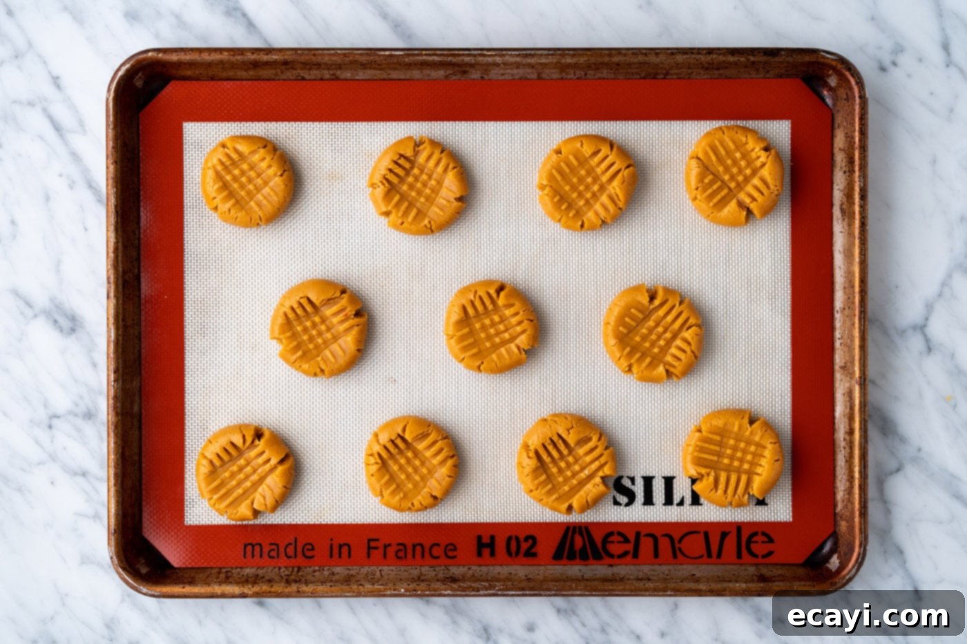 Peanut Butter Cake Mix Delights 14 Unbaked peanut butter cookie dough balls with cross-hatch patterns on a baking sheet.