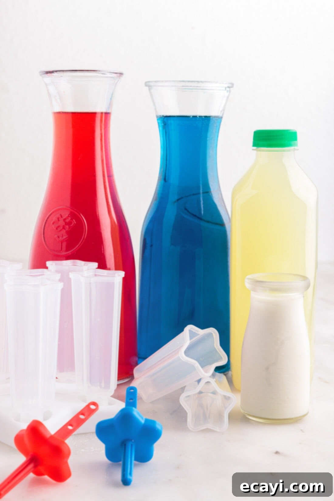 Stars & Stripes Freeze Pops 4 All the vibrant ingredients for making Patriotic Bomb Pops laid out: cherry and blue raspberry Kool-Aid, limeade, and heavy whipping cream.
