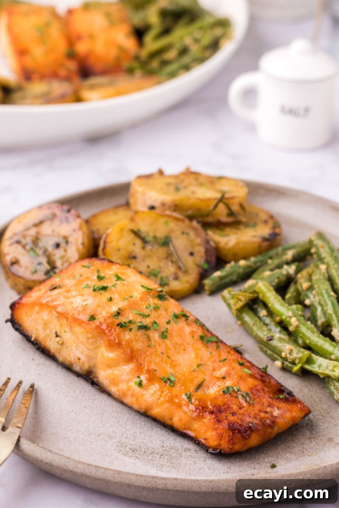 Caramelized Salmon 10 Brown Sugar Salmon served on a white plate with a side of golden melting potatoes and vibrant garlic green beans.