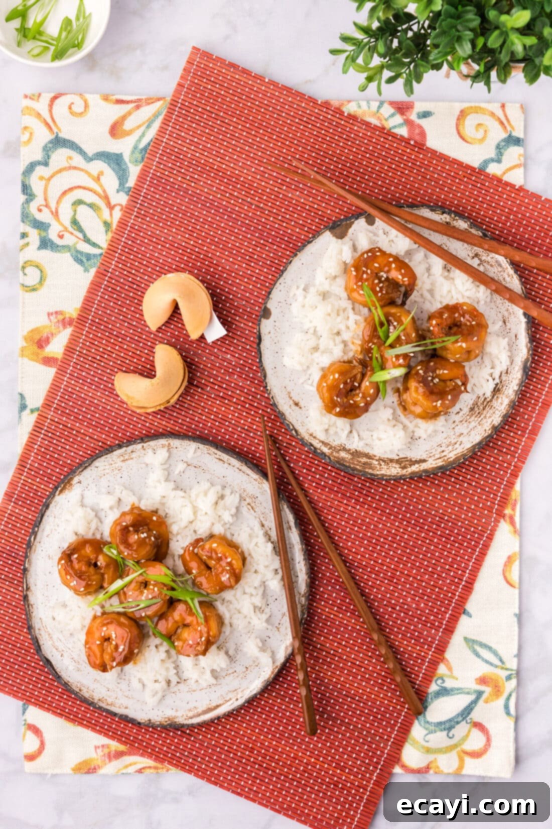Fiery Hunan Shrimp 2 Two plates of Spicy Hunan Shrimp served with white rice, garnished with green onions and sesame seeds, alongside chopsticks and fortune cookies