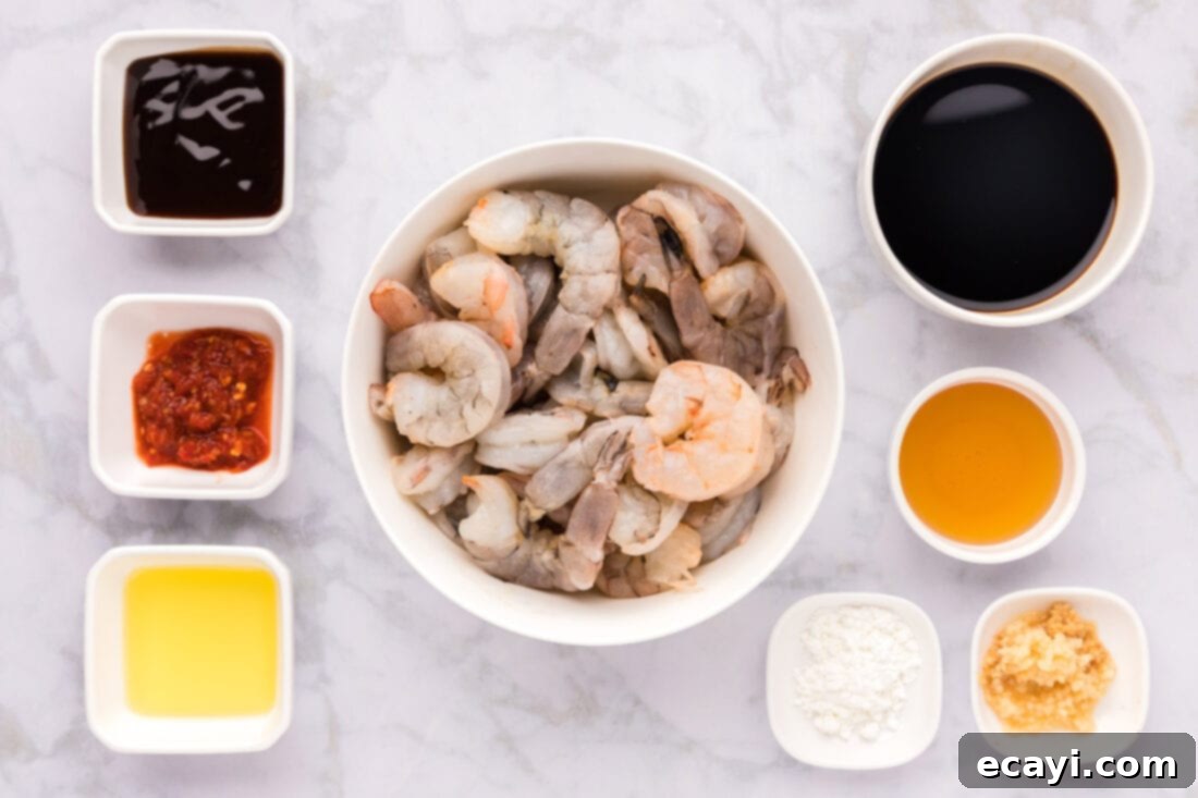 Fiery Hunan Shrimp 4 A collection of fresh ingredients for Hunan Shrimp, including raw shrimp, various Asian sauces, honey, garlic, and cornstarch, neatly arranged on a counter.