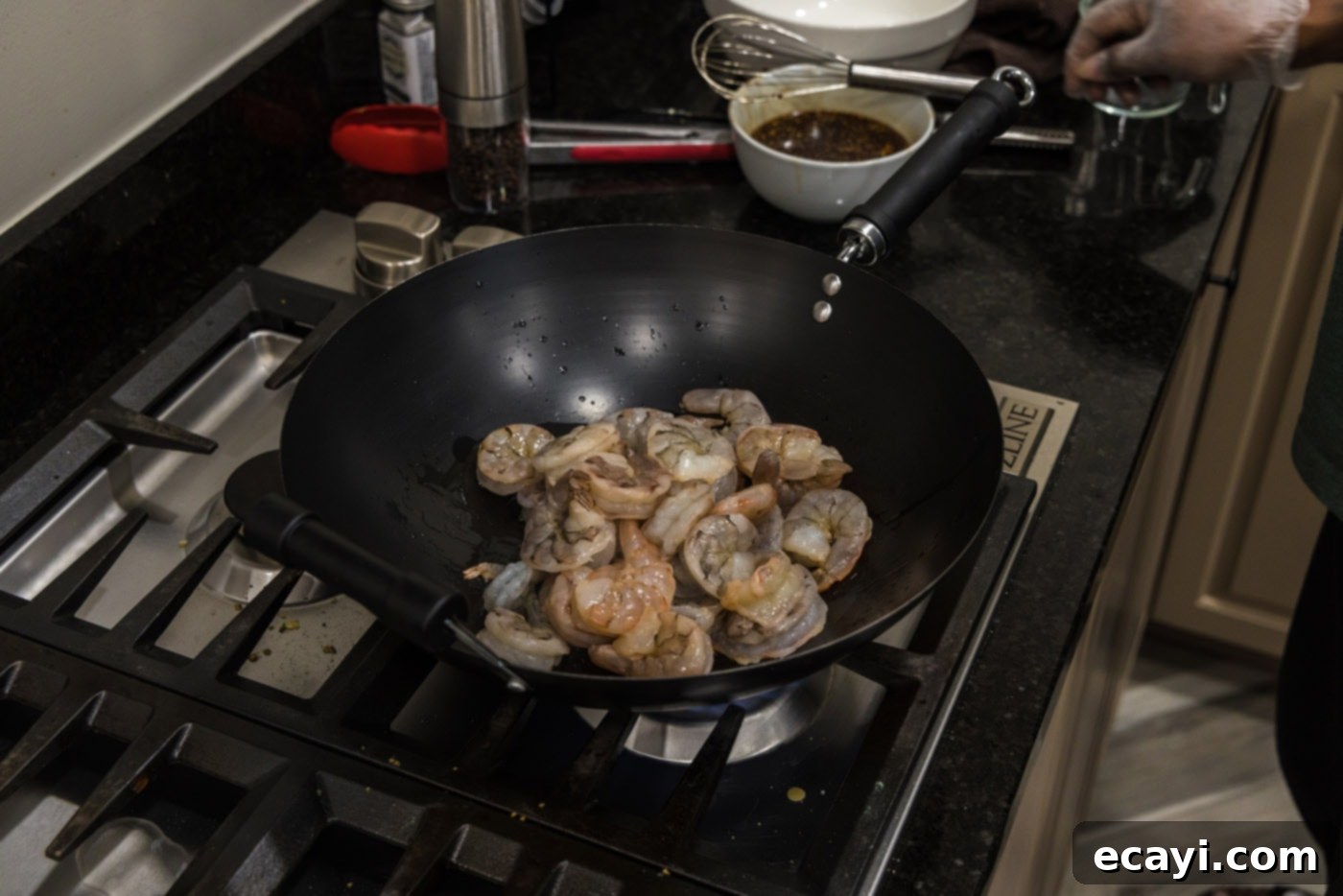 Fiery Hunan Shrimp 5 Stir-frying raw shrimp in a hot wok with olive oil until they turn pink and opaque