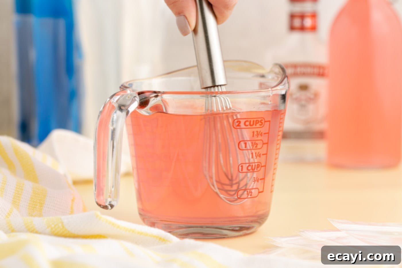 Poptails 6 whisking juice and vodka in a cup, ensuring a well-mixed blend.