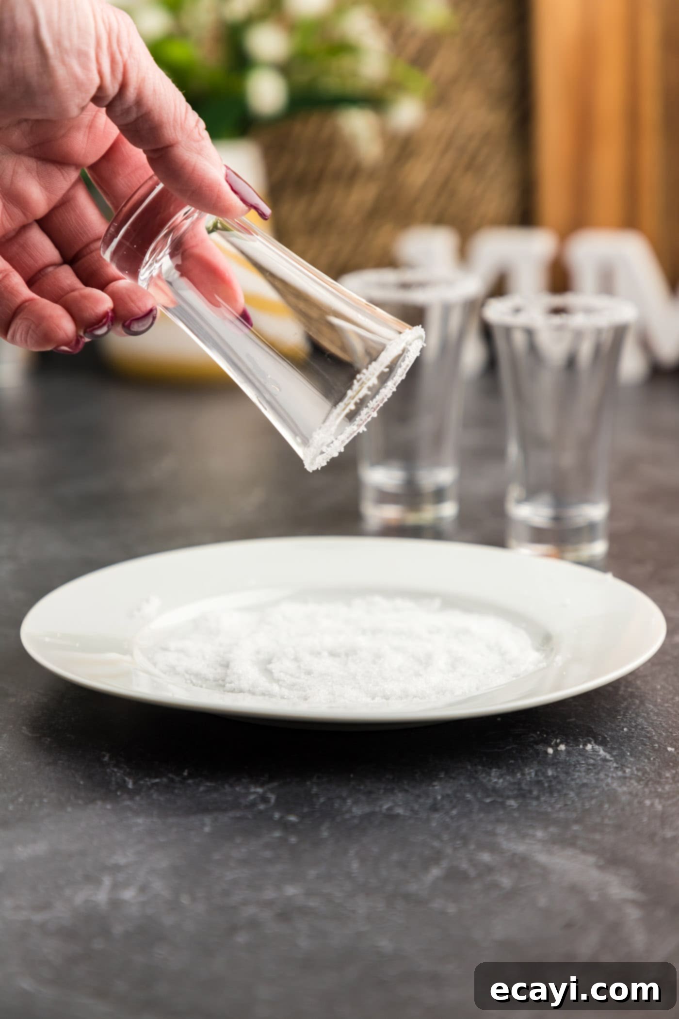 Salted Caramel Nut Blast 5 Dipping wet shot glass rim into a pile of salt on a plate