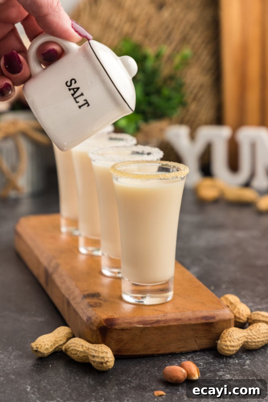Salted Caramel Nut Blast 9 Salt shaker held above a row of Salted Nut Roll Shots, emphasizing the salty aspect