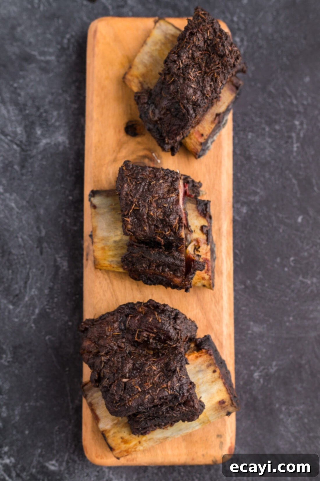 Melt in Your Mouth Smoked Short Ribs 9 Three Smoked Beef Short Ribs on a wooden serving platter, ready to be enjoyed