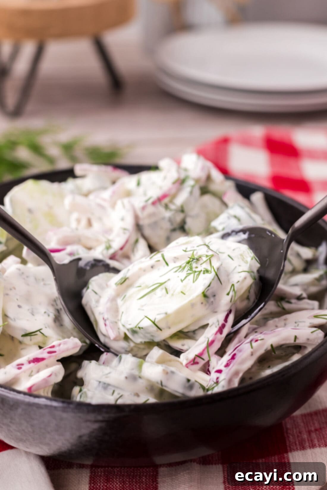 Cool and Creamy Cucumbers 3 Two spoons elegantly placed in a bowl of freshly prepared Creamy Cucumber Salad, ready to be served.