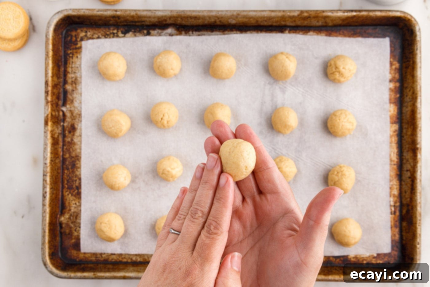 No-Bake Golden Oreo Bliss 12 Hands rolling an Oreo truffle ball to make it smooth.