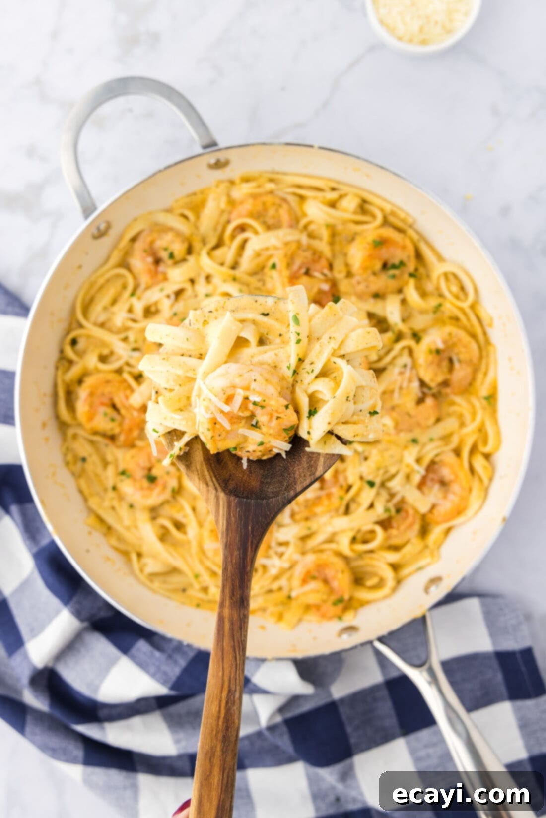 Shrimp Alfredo Bliss 2 A spoon lifting creamy shrimp alfredo from a skillet, showcasing the rich sauce and plump shrimp