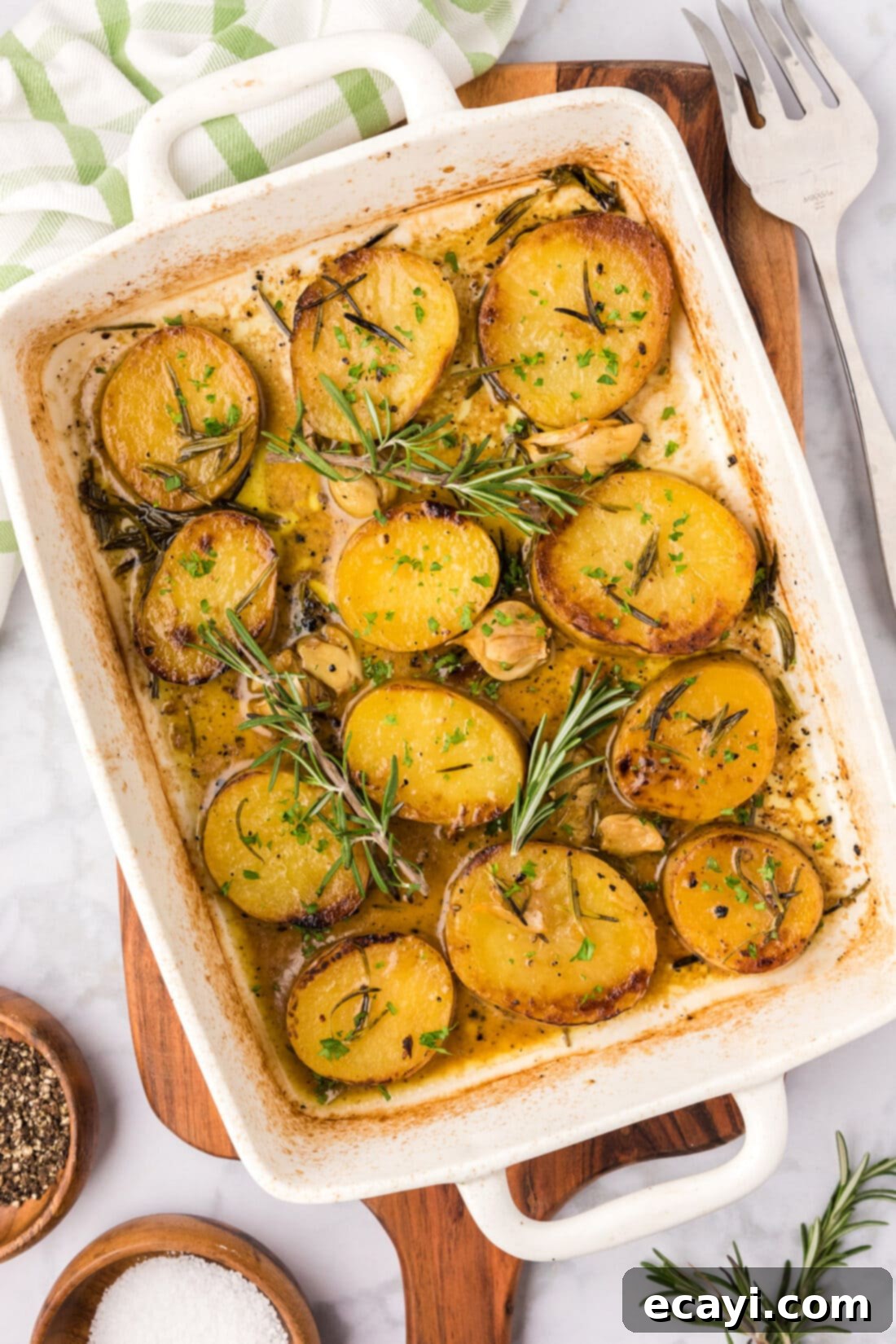 Ultra-Tender Melting Potatoes 2 Melting Potatoes in a baking dish with rosemary garnish