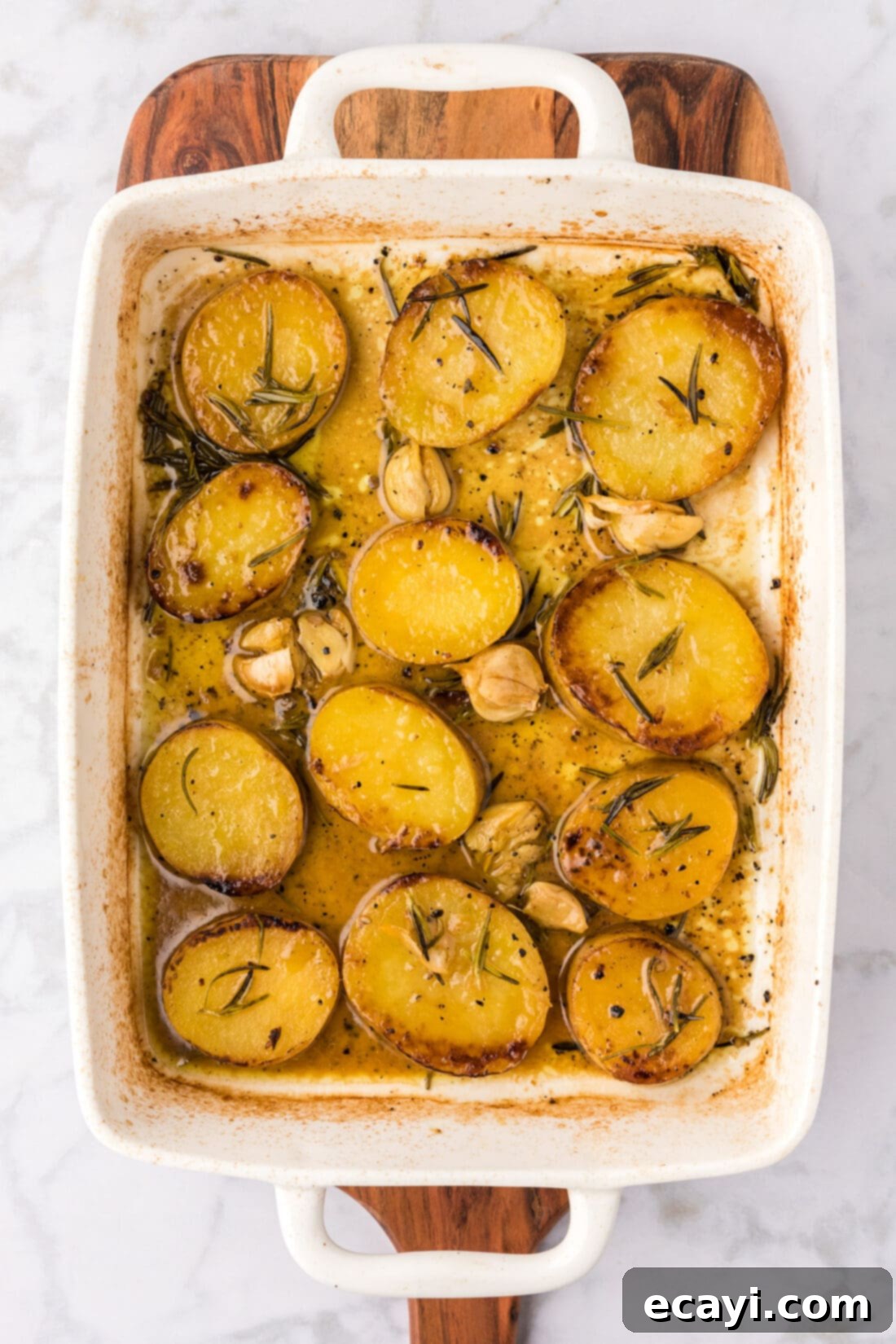 Ultra-Tender Melting Potatoes 13 Baking dish of Melting Potatoes resting on a wooden platter