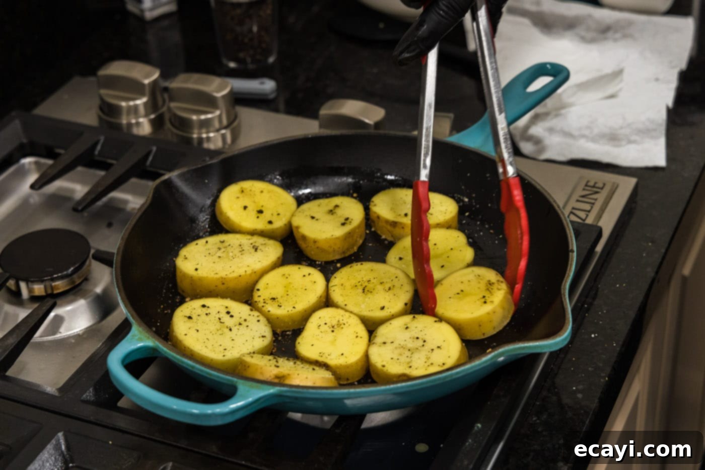 Ultra-Tender Melting Potatoes 7 tongs turning over potato rounds in a skillet