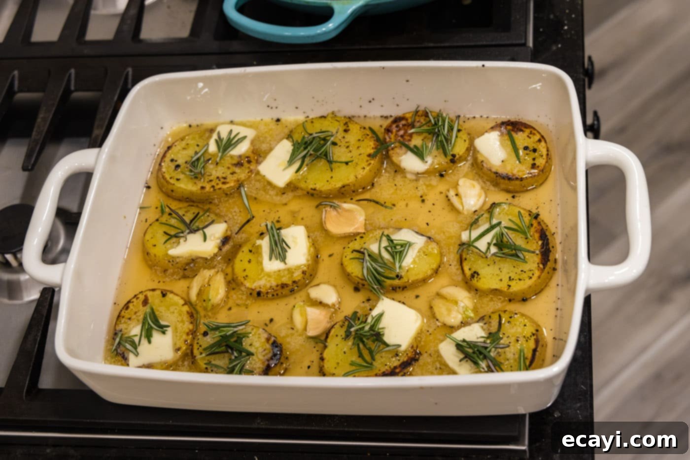 Ultra-Tender Melting Potatoes 10 potato slices in a baking dish with chicken broth, rosemary, and garlic