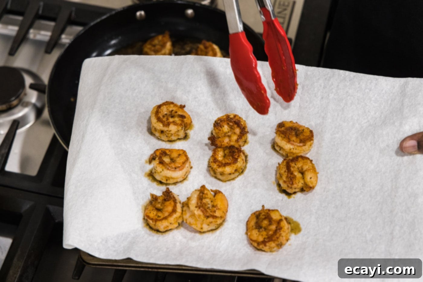 Fiery Cajun Prawns 8 tongs moving cooked shrimp to a paper towel to drain