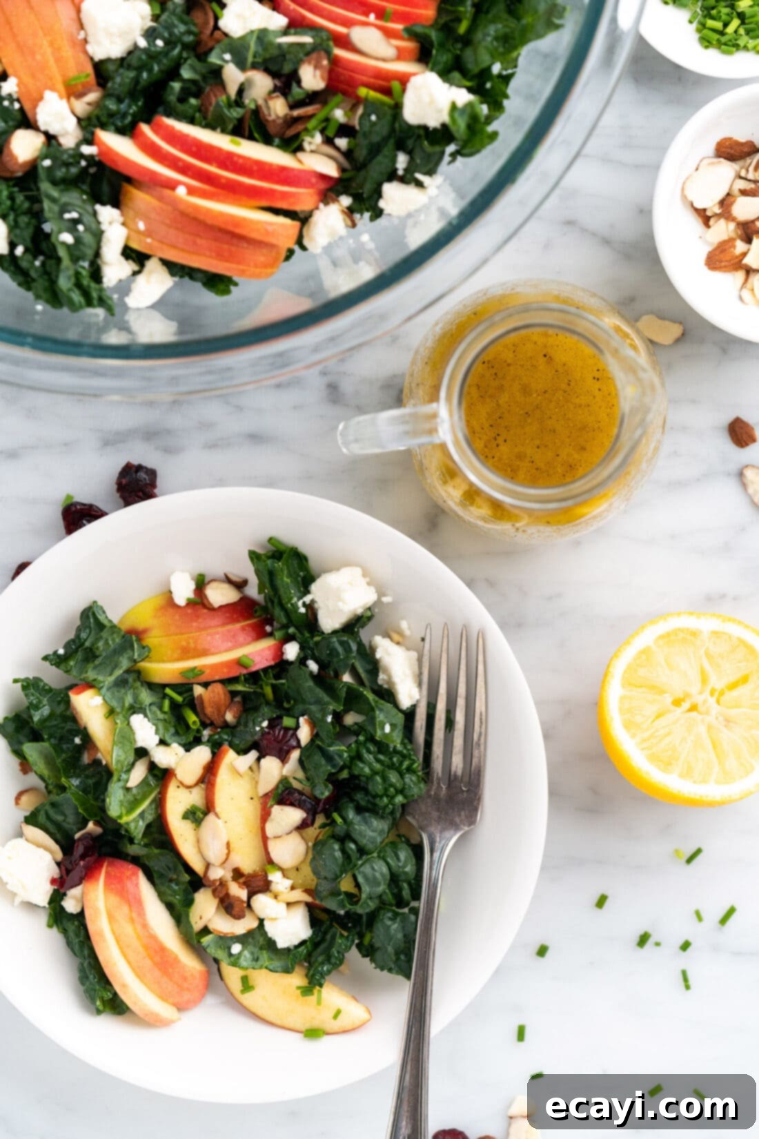 Zesty Lemon Vinaigrette 3 Lemon Salad Dressing in a dressing container surrounded by a plate an bowl of Kale Salad