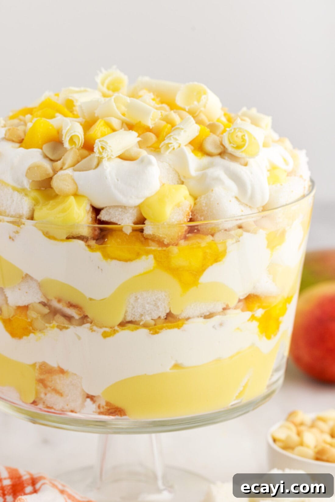 Golden Mango Indulgence 2 Close up photo of a Mango Trifle, showcasing its beautiful layers of cake, pudding, mango, and whipped cream, topped with macadamia nuts.