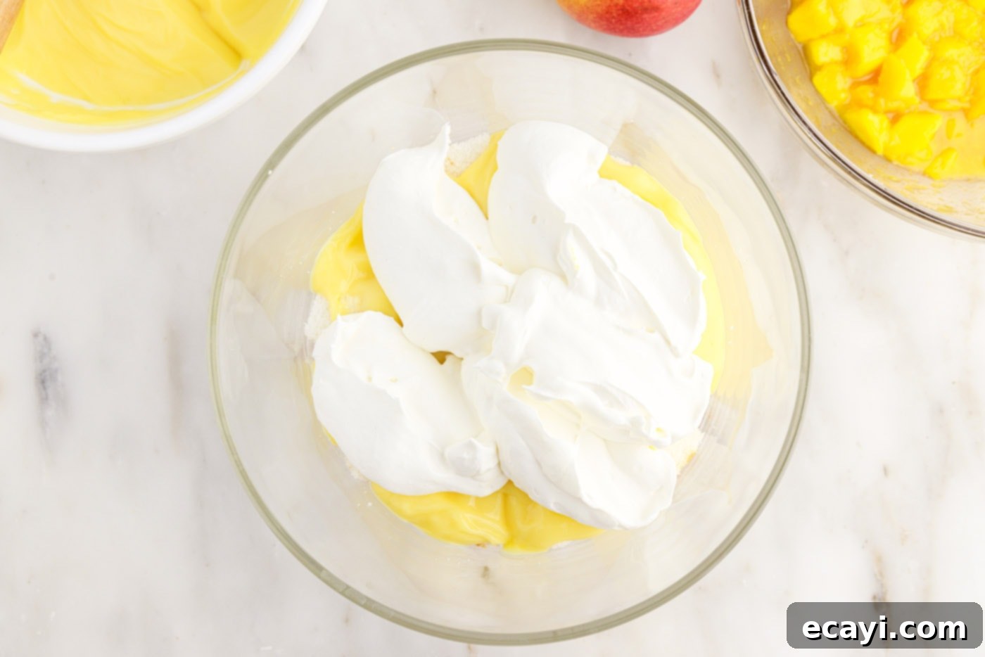 Golden Mango Indulgence 11 A fluffy layer of whipped cream carefully placed over the pudding and angel food cake layers in the trifle dish.
