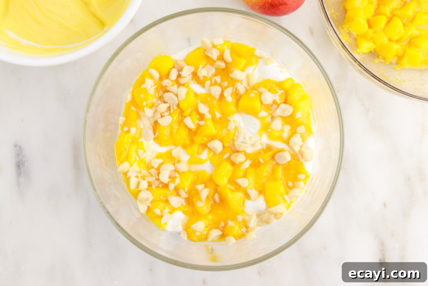 Golden Mango Indulgence 12 A vibrant layer of diced mangoes and chopped macadamia nuts completing a section of the trifle, over whipped cream, pudding, and cake.