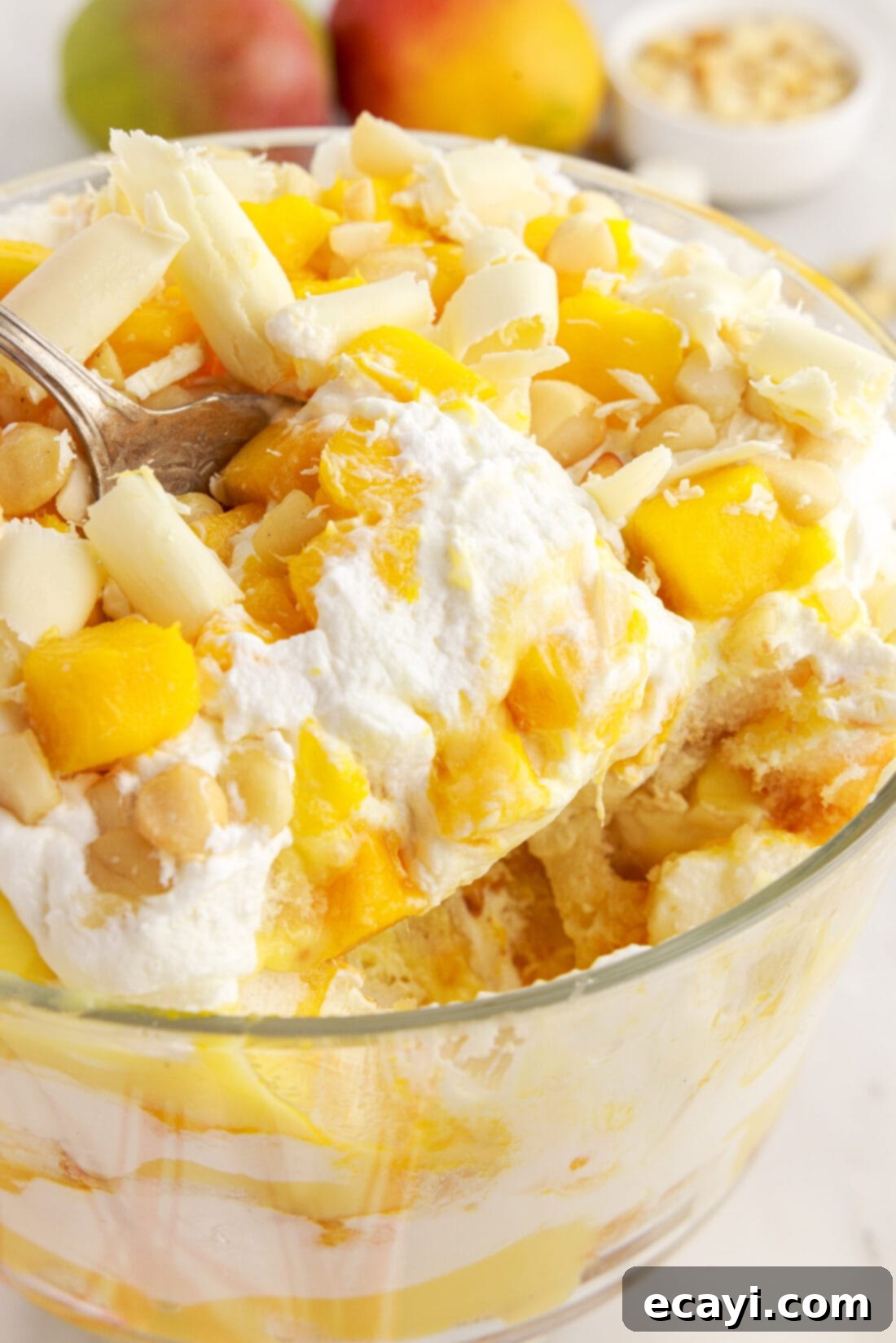 Golden Mango Indulgence 3 A scoop of Mango Trifle being lifted from a large glass trifle dish, showing the distinct layers and inviting texture.