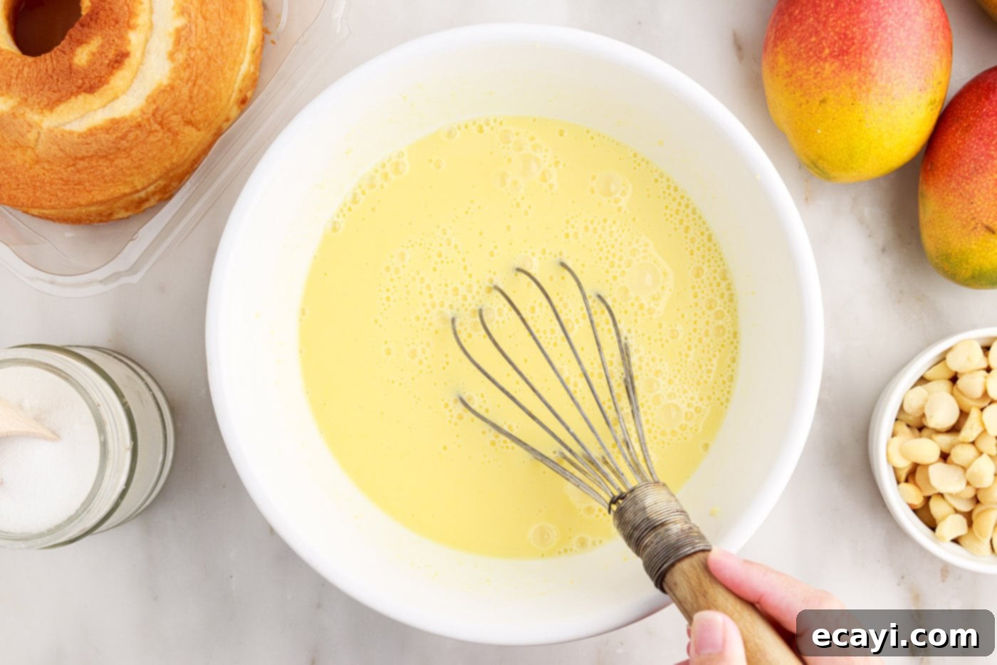 Golden Mango Indulgence 6 A whisk vigorously mixing instant vanilla pudding in a bowl until it thickens to a smooth consistency.