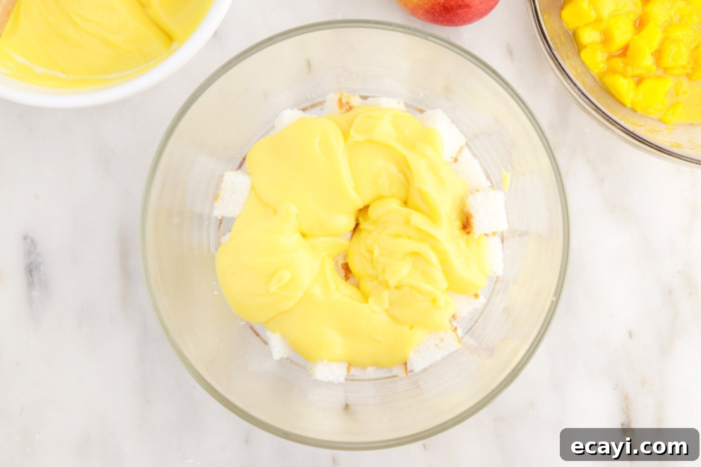 Golden Mango Indulgence 10 Smooth layer of vanilla pudding spread over the angel food cake in a trifle dish.