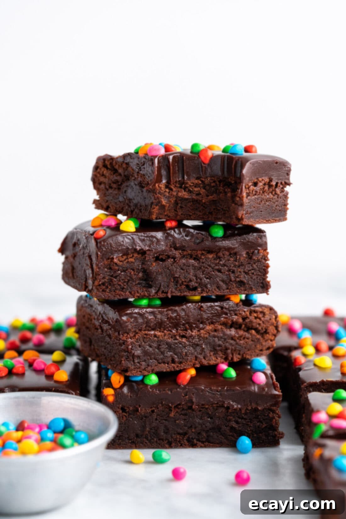 Dark Matter Delights 2 Stack of Cosmic Brownies with a bite taken out of the top brownie, showcasing the fudgy interior and colorful sprinkles