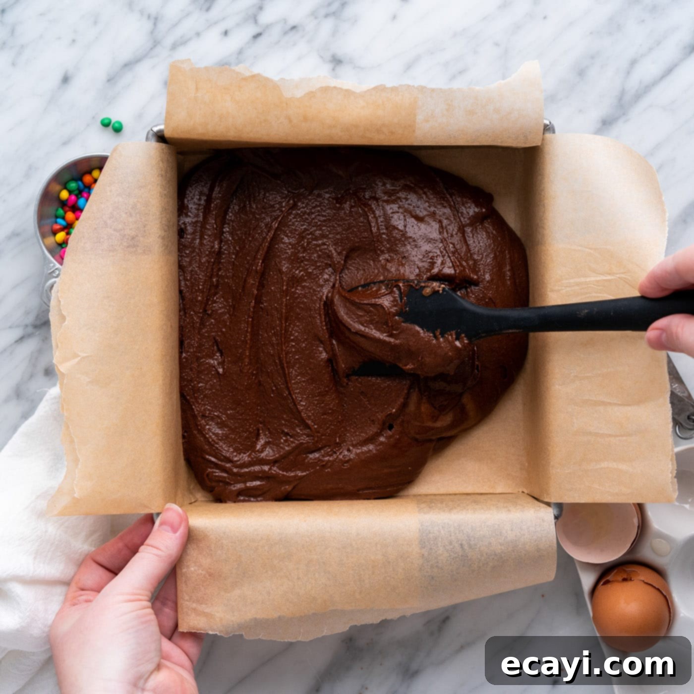 Dark Matter Delights 14 Spreading thick brownie batter evenly into a parchment-lined baking pan.