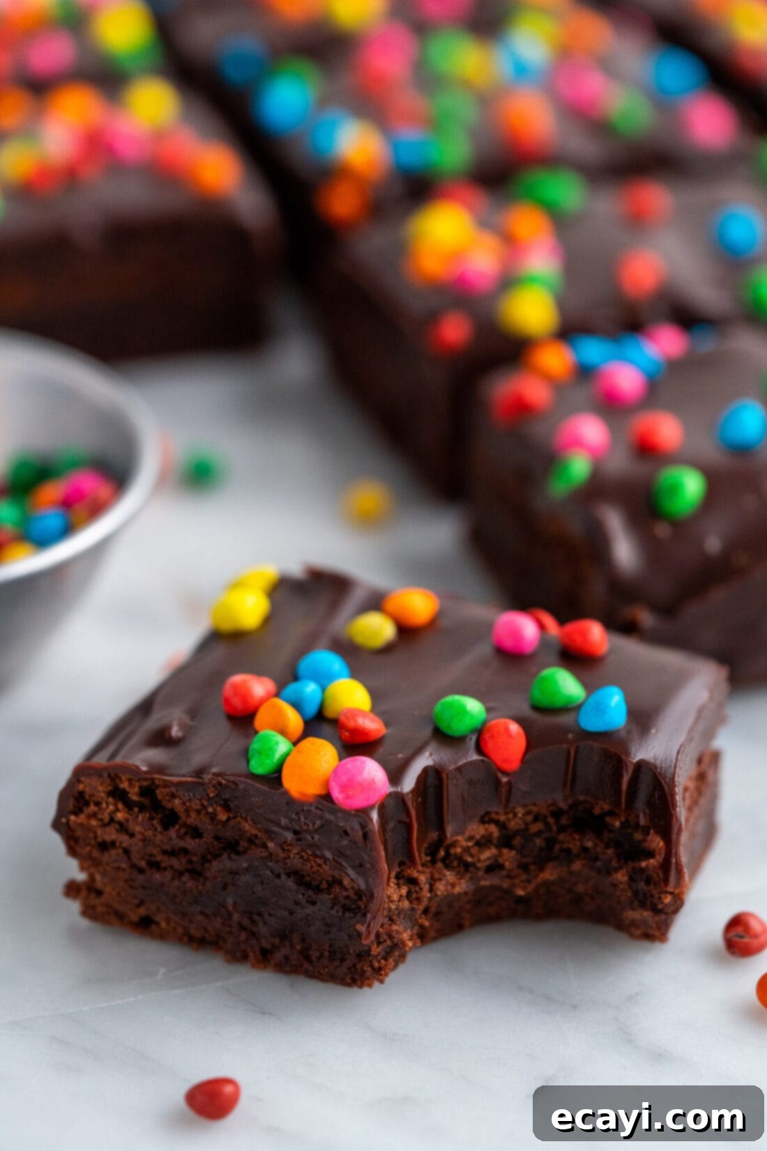 Dark Matter Delights 3 Close up photo of a Homemade Cosmic Brownie with a bite taken out, showing the thick ganache and colorful sprinkles.