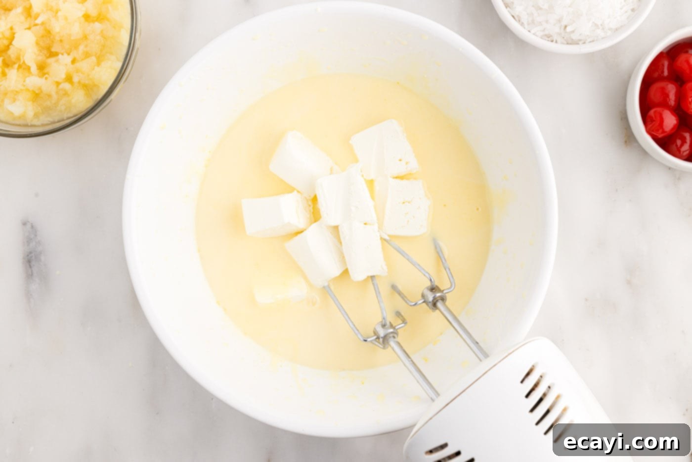 Billionaire Bliss Cake 9 Blending softened cream cheese into the pudding mix using a hand mixer, ensuring a smooth, creamy texture.