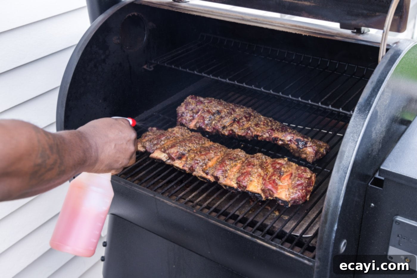 Pitmaster's Smoked Beef Ribs 7 spraying beef ribs with apple cider vinegar mix on the smoker