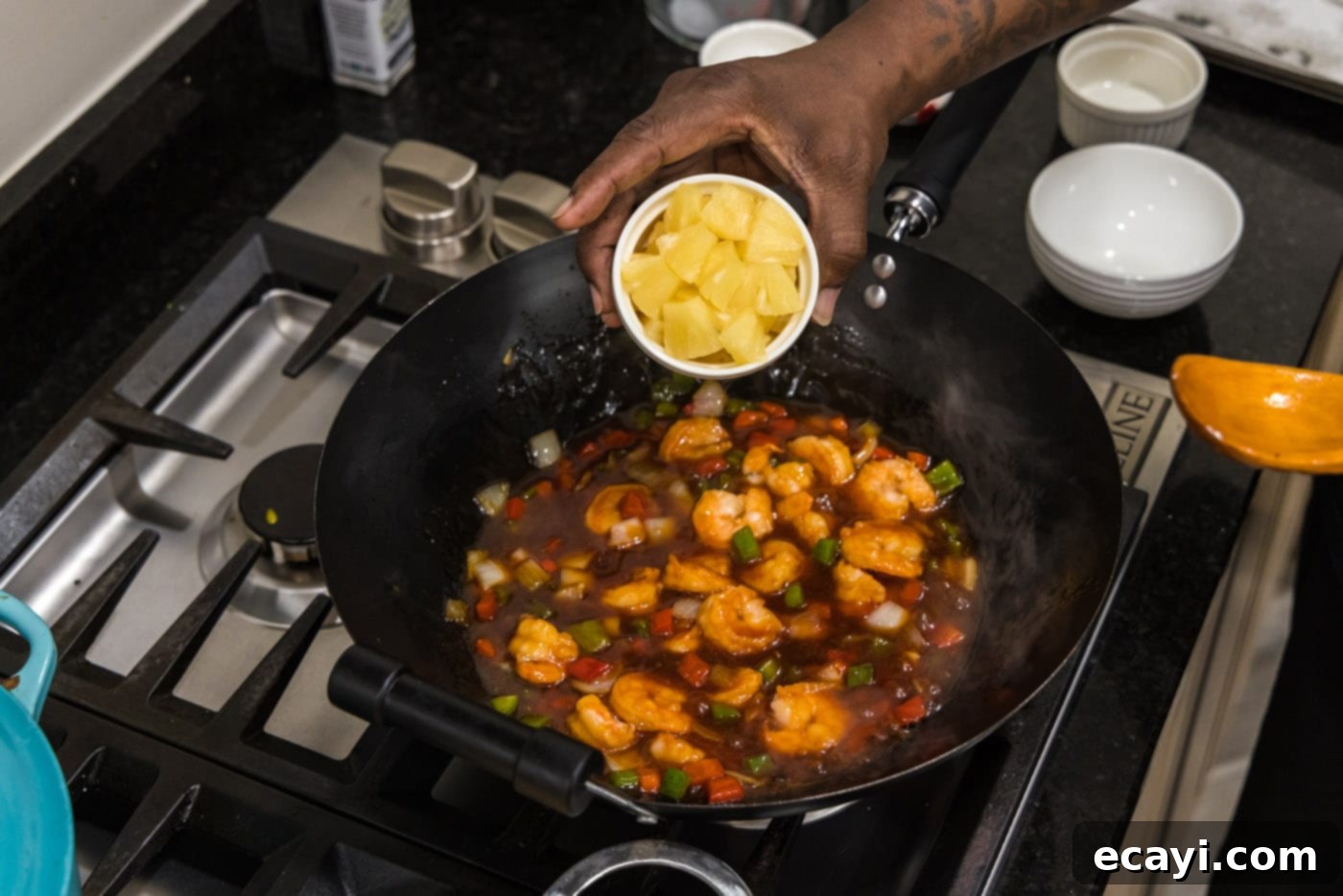 Tangy Prawn Delight 13 Adding pineapple wedges to the sweet and sour shrimp dish in the skillet.