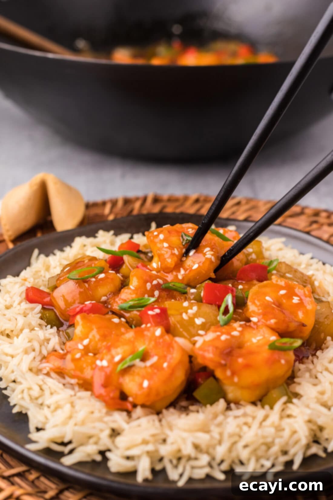 Tangy Prawn Delight 3 Sweet and Sour Shrimp on a plate served over rice with chopsticks, ready to be enjoyed.