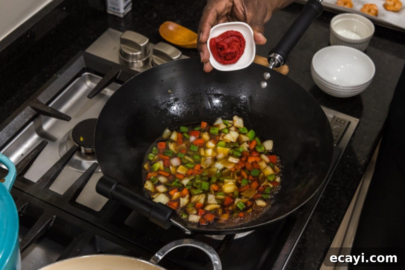 Tangy Prawn Delight 10 Tomato paste being added to the skillet with vegetables and sauce ingredients.