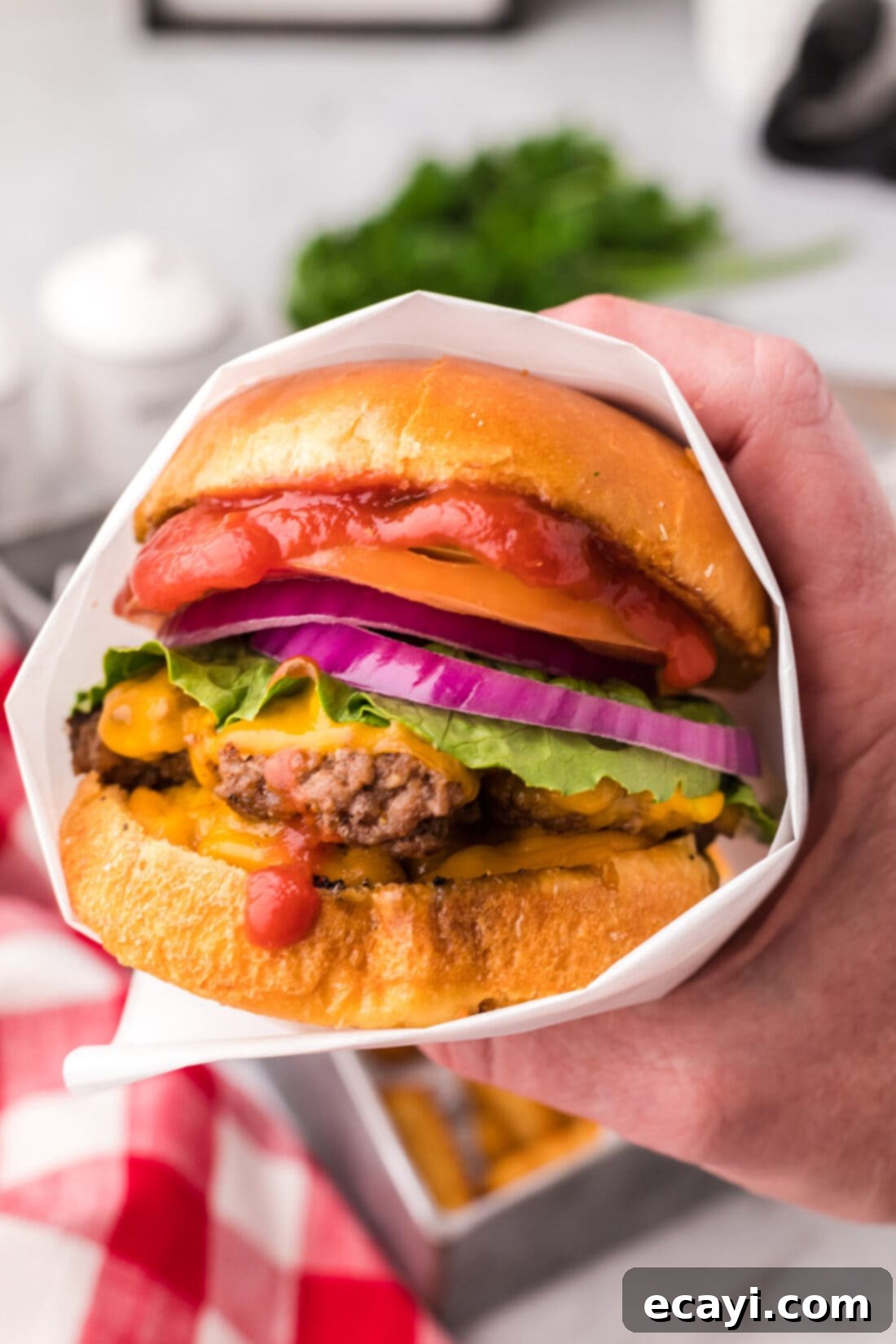 The Smash Burger 3 Hand holding a Smash Burger wrapped in parchment paper