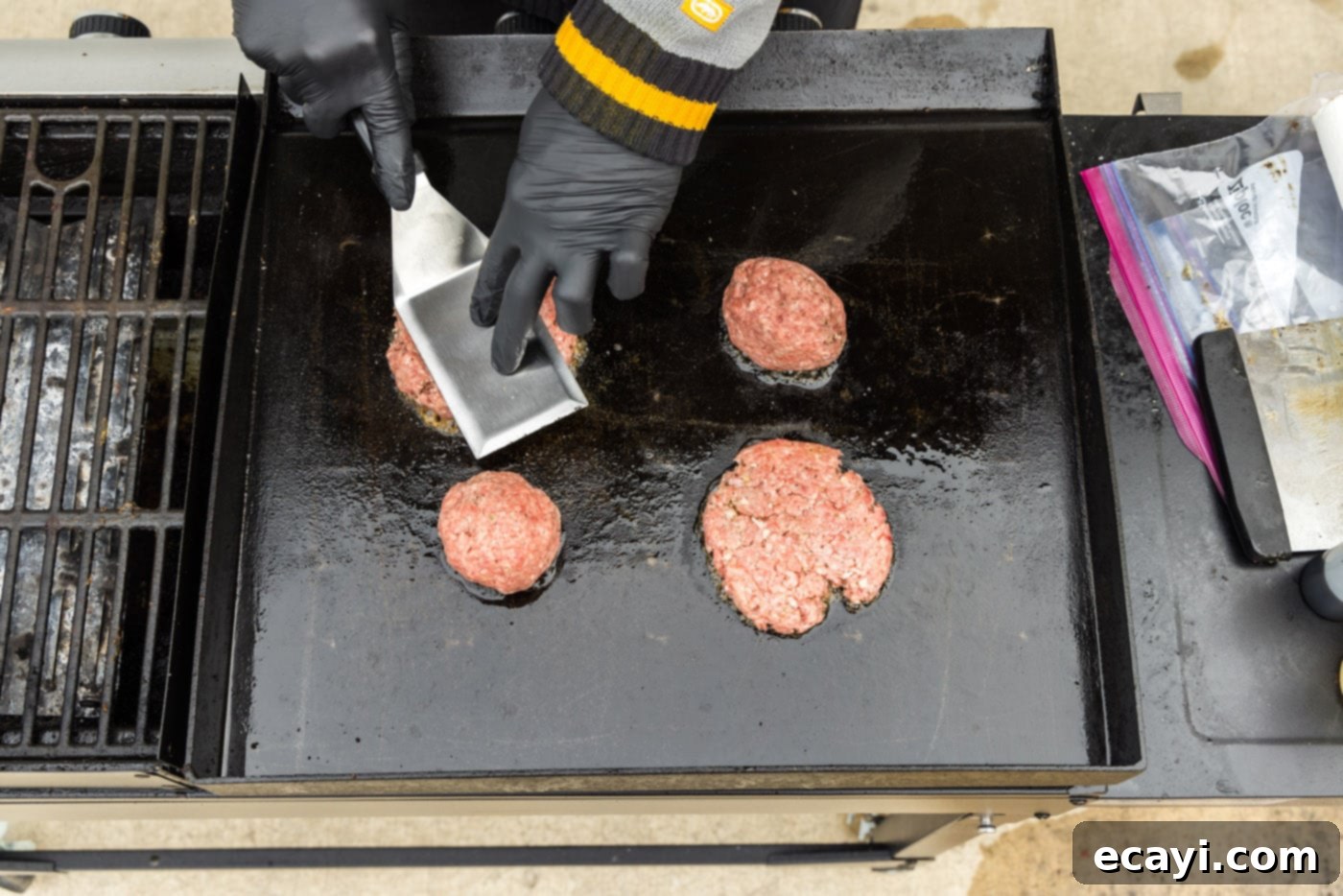 The Smash Burger 9 pressing down on burger patties on a griddle