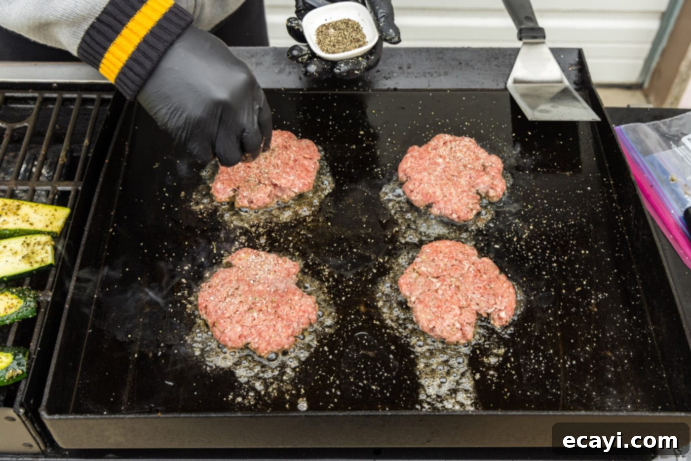 The Smash Burger 10 sprinkling seasonings on top of burger patties